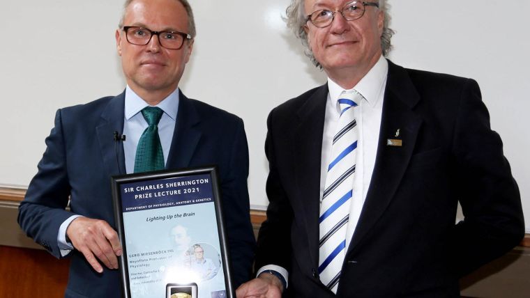 Professor David Paterson presents the Sherrington Prize Lecture speaker Professor Gero Miesenböck with a framed poster of the Lecture and the Sherrington Prize Medal.